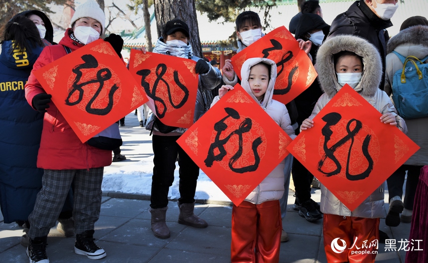 書法家揮毫潑墨書寫“龍”字，市民領取后進行展示。人民網 蘇靖剛攝