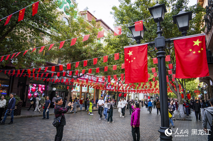 哈爾濱中央大街掛起了五星紅旗，許多市民游客在此拍照留念。人民網(wǎng)記者 張哲鑫攝